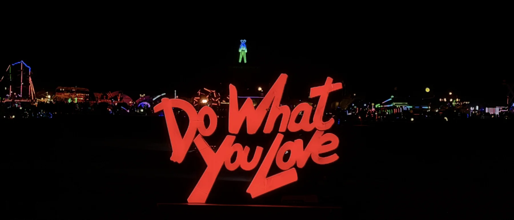 A hand-lettered “Do What You Love” sculpture lit up on the playa, a night landmark for everyone passing by.